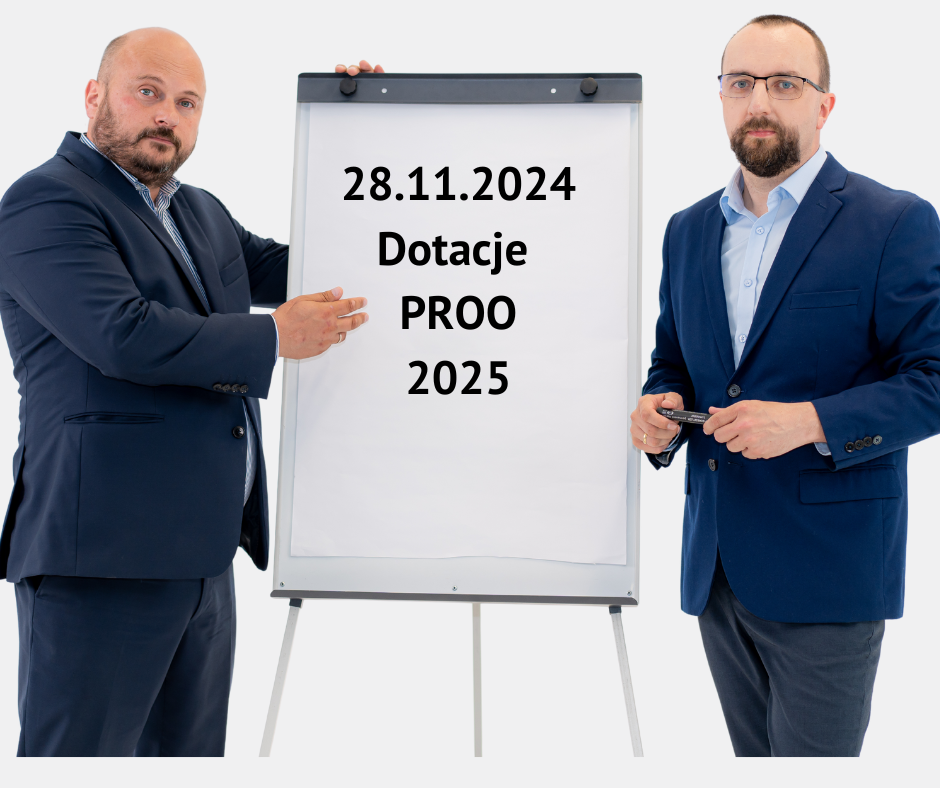 Obrazek przedstawia Waldka Żbika i Witka Ekielskiego, którzy stoją przy flipchartcie na którym jest napisane: "28.11.2024 Dotacje PROO 2025"